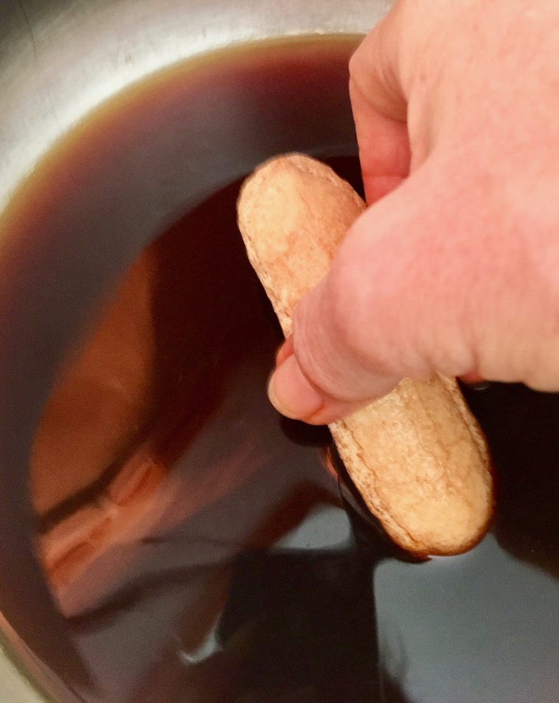 A lady finger being dipped into coffee. A lady finger being dipped into coffee.