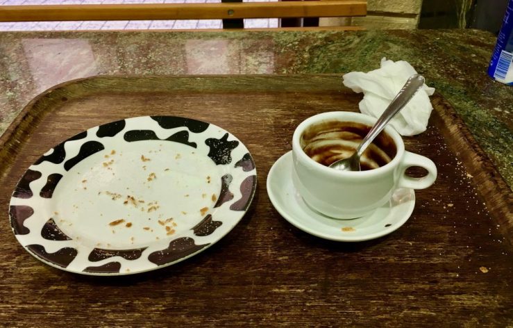 empty mug and plate of churros and hot chocolates
