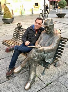 Photo of da-AL's husband sits with statue of Antoni Gaudí.