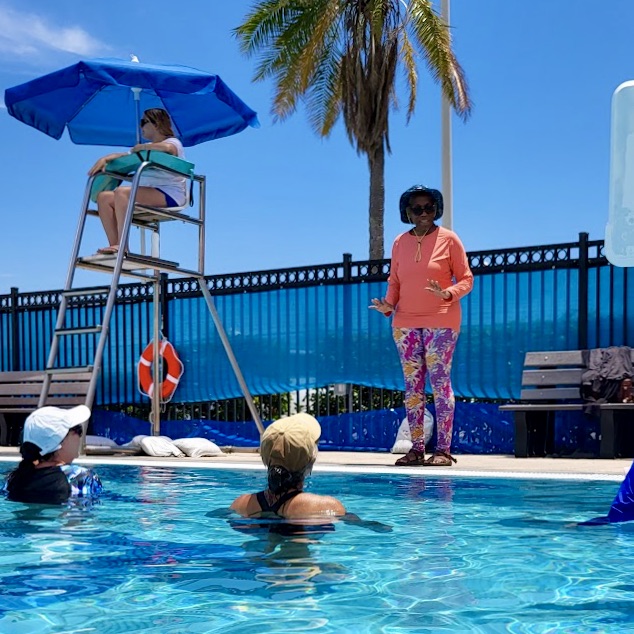Janina Edwards leading an Aqua Yoga class at an outdoor pool. Photo by Christa Fairbrother. 