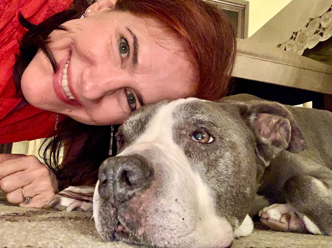 Selfie of da-AL touching her forehead to a grey and white pitbull's forehead.