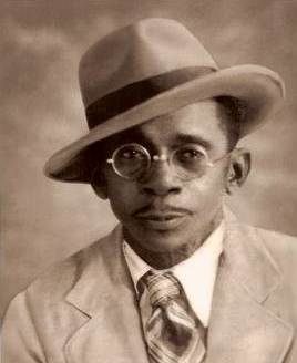 Vintage black and white photo of Jerrice J. Bapitste’s Great grandfather Laurore fashionably dressed in a suit and hat.