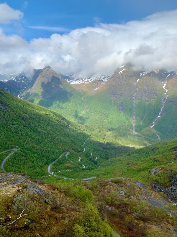 Photo of green mountains with long snaking roads near Vik, Norway.
